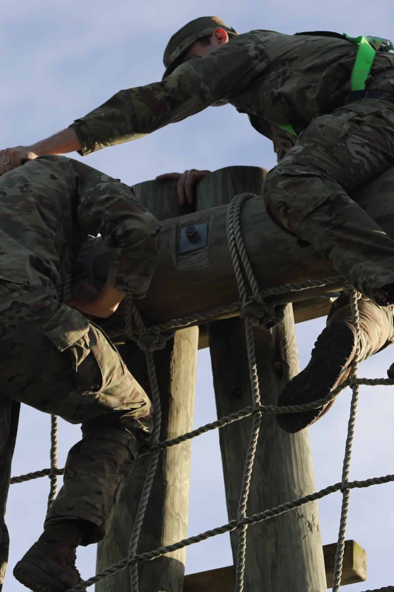 A group of soldiers climbing a wooden structure.