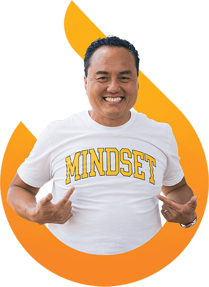 Smiling man in a white T-shirt with the word "MINDSET" printed in yellow, standing in front of an orange flame-shaped graphic.