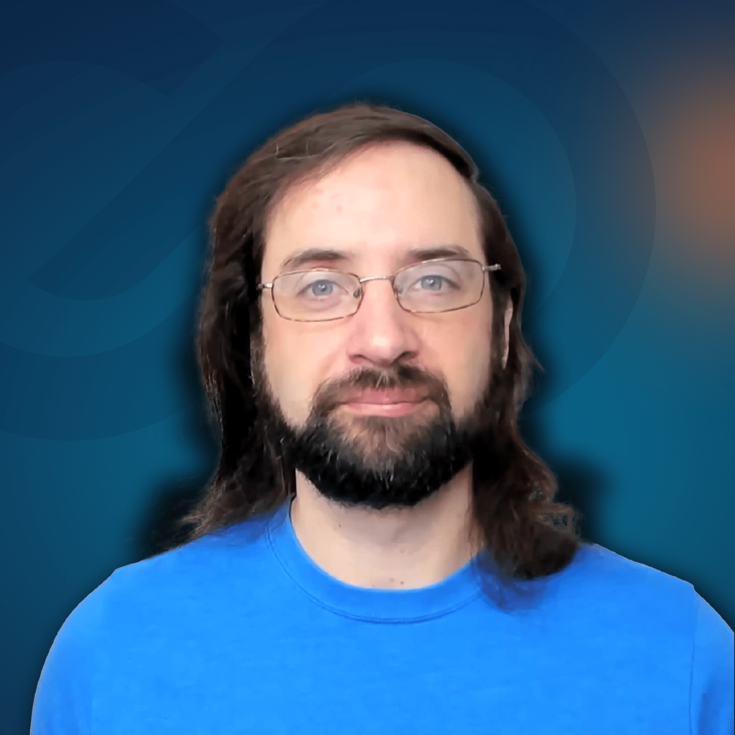 A person with long brown hair, a beard, and glasses, wearing a blue shirt, is facing the camera against a gradient blue background.