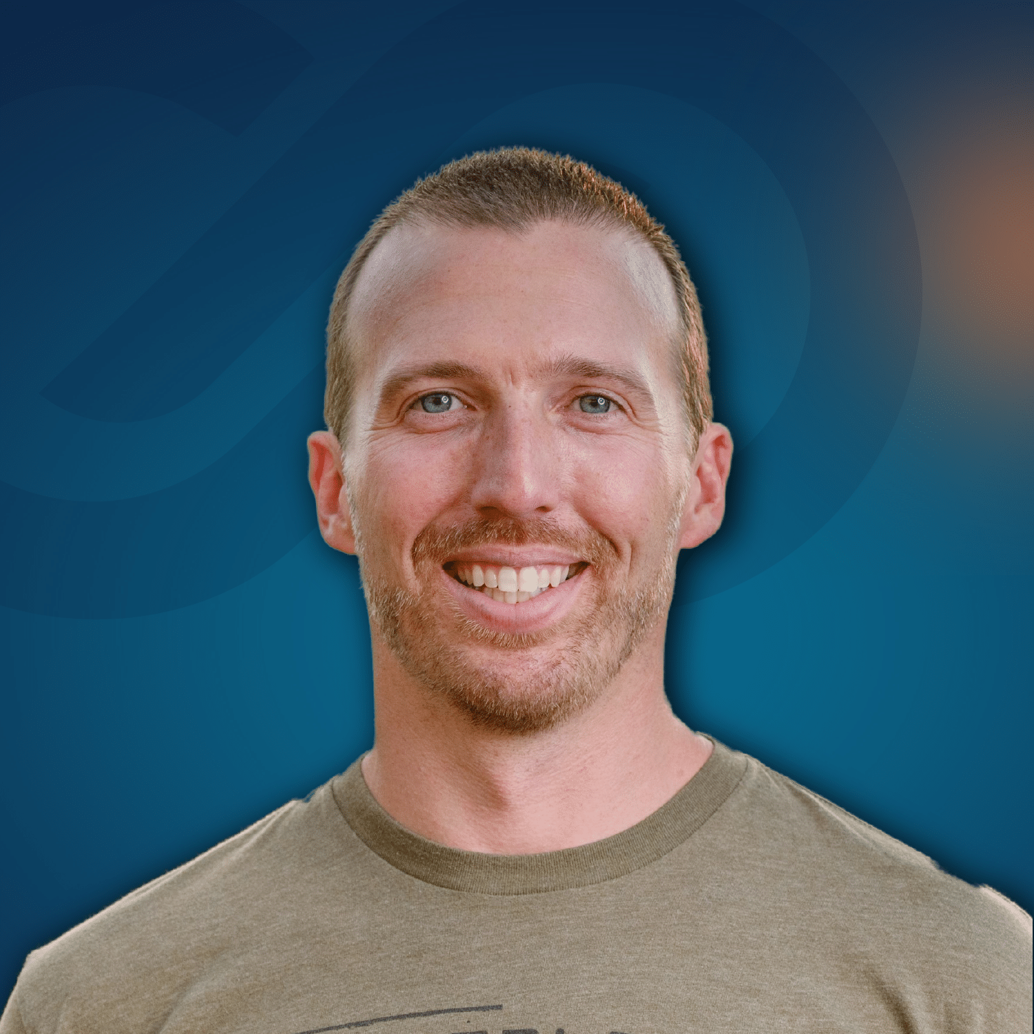 A man with short hair and a trimmed beard smiles at the camera. The background is blue with a subtle abstract design.